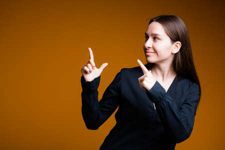 Girl on orange background shows different emotions and hands in the black shirtの写真素材