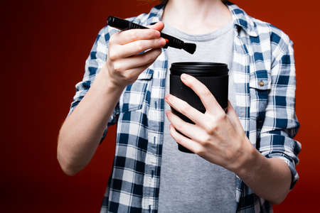 Close-up of the torso and hands of a girl in a plaid shirt that cleans the macro lens of the camera...