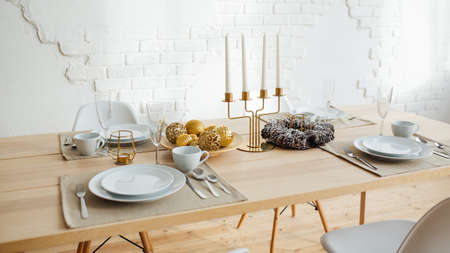 New Years table setting. Christmas wreath, candles, tree. Beautiful festive interior