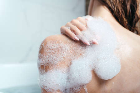 Close-up of a female shoulder in foam. The girl takes a bath with foam. Body care, skin care, asparagus proceduresの写真素材