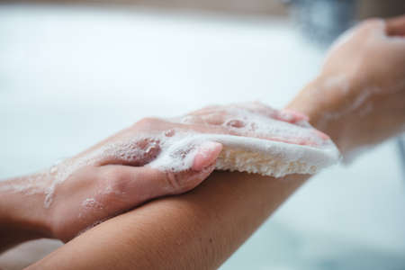 The girl takes a bath and washes her body with a washcloth for a shower. Bath foam, shower gel, body...