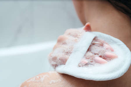 Womans shoulder close-up. The girl lathers her shoulder with a washcloth, sits in the bath. Skin and body care. Relaxation. asparagus proceduresの写真素材