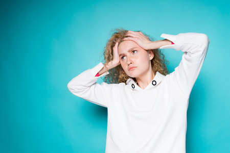 tired woman holding her head with two hands and headache migraine upset lookの写真素材