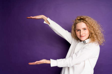 playful woman shows with her hands to the free space on the background for the inscription. curls on...
