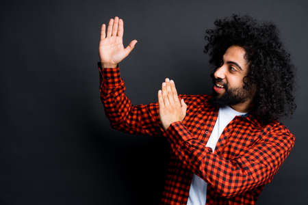 African American man stands on a dark background and shows with his hands to the sideの写真素材