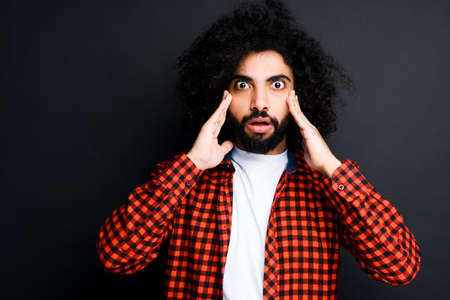 Handsome egyptian with afro hairstyle fearfully touches his temples with his handsの写真素材