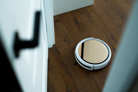 The circular vacuum cleaner on the remote control works by collecting dust on the floorの写真素材