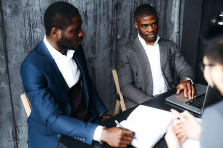 Two African American men in business classic suits, teachers at the university are sitting at a meeting at the table in the officeの写真素材