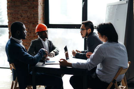 African american businessmen and workers with asian appearances sit at the table communicating at the meetingの写真素材