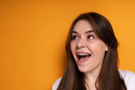 Happy young girl laughs with her mouth wide open rejoicing in the installation of braces and looks...