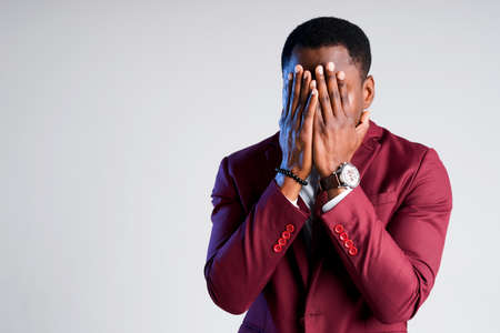 Tired african american businessman covers his face with his palms from long workの写真素材