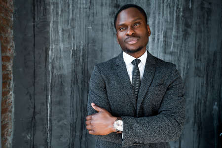 Handsome african american businessman stands with his arms crossed over his chest and looking at the cameraの写真素材