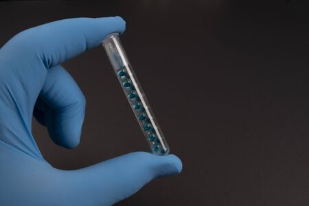 Corona virus pandemic concept:  A hand with medical hygienic protection glove is holding a test tube...