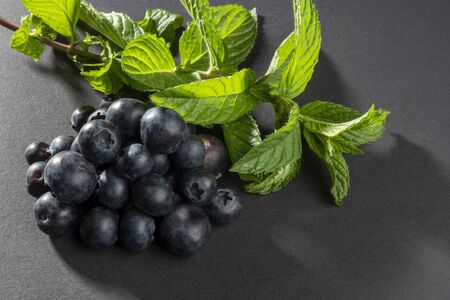 Bio blueberry fruits stacked to a pyramid shape with some peppermint leaves.の写真素材