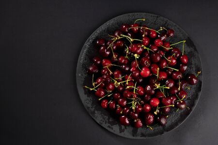 Top view on fresh, wet, dark cherries. Water drops on bright shiny dark red fruits with stalks....