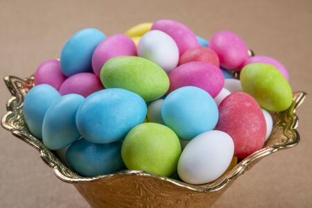 Close up of many colorful sugared sweet almond candies stacked like a pyramid in a golden ornate...