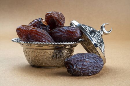 Religious iftar Ramadan concept: Side view of few dried organic sweet date fruits in a silver...