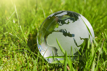 World globe made of glass, earth with grass and sun, nature protection, environmental protection, climate protectionの写真素材