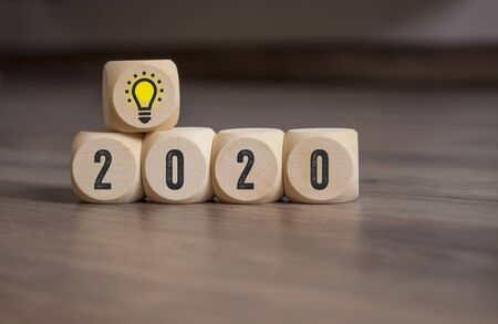 Cubes and dice with lightbulb and 2020 on wooden backgroundの写真素材