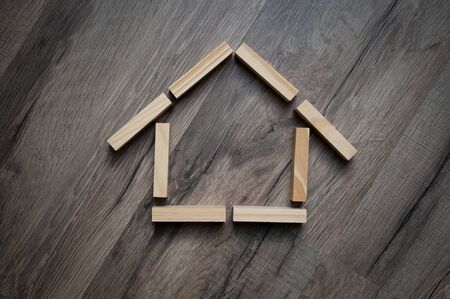 House made of wooden pieces on wooden background metaphor for dream of home ownership
