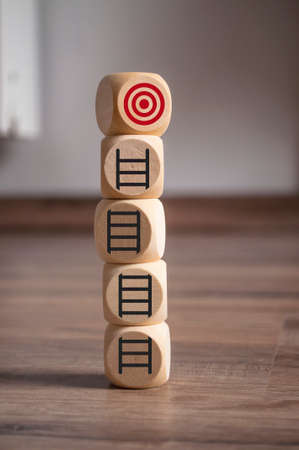 Tower made of cubes, dice or blocks with a career ladder and target on wooden backgroundの写真素材