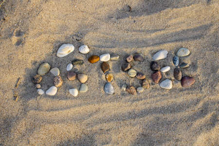 The german word Ostsee - baltic sea made with pebbles in the sand at sunsetの写真素材