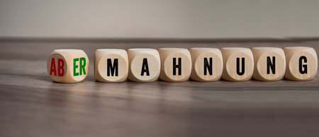 Cubes, dice or blocks with the german words for warning and admonition - abmahnung und ermahnung on wooden backgroundの写真素材