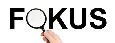 Hand with magnifying glass showing the word focus - and german focus isolated on white background