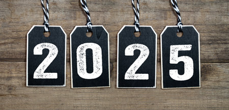 Black wooden hang tags or miniature slate plates with 2025 on wooden weathered backgroundの写真素材