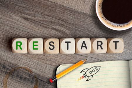 Cubes, dice or blocks with message restart with cup of coffee and sketchbook and pencilの写真素材