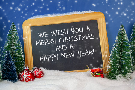 Christmas decoration with miniature trees and slate plate with we wish you a merry Christmas and a...