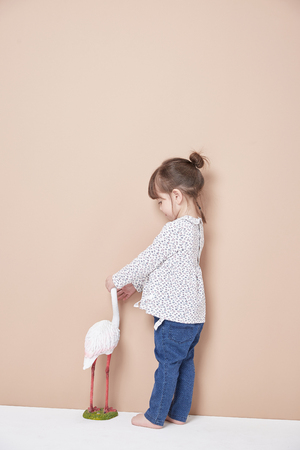 The little girl in jeans wears a naughty look in front of the background wall.の写真素材