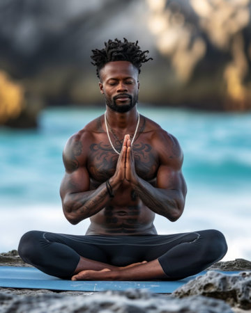 A man sits on top of a blue yoga mat, practicing yoga or meditation.の素材