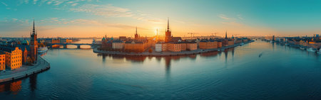 A city skyline with a river running through it. The sun is setting, casting a warm glow over the buildingsの素材