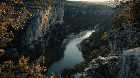 Golden light illuminates the cliffs surrounding a winding river, creating a peaceful atmosphere in a picturesque natural setting. The serene water reflects the evening hues.の素材