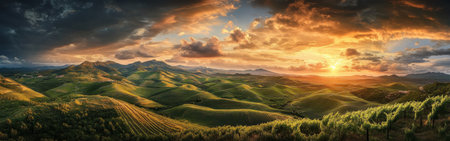 The vibrant sunset casts warm hues across rolling green hills, with dramatic clouds accentuating the peaceful countryside during the golden hour of the evening.の素材