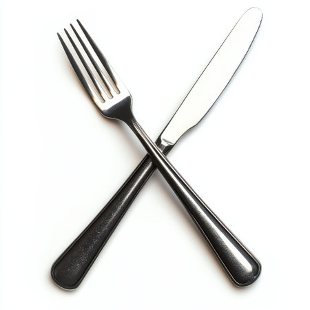 A fork and a knife are artistically arranged in a crossed position on a clean, white surface, symbolizing readiness for a meal or dining experience.の素材