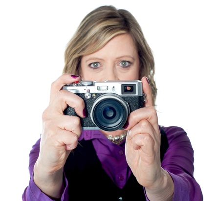 Portrait of a beautiful woman using camera against a white backgroundの写真素材