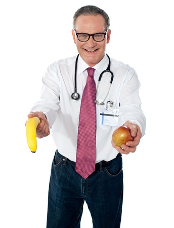 Senior doctor offering fruits to you for your good healthの写真素材