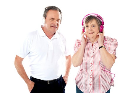 Happy aged couple enjoying music together in studio. Isolated over whiteの写真素材