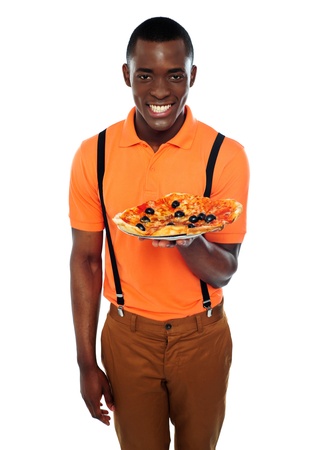 Smiling young african boy offering delicious pizza isolated against white backgroundの写真素材