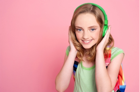 Pretty teenager enjoying music on headphones with bag on her shouldersの写真素材
