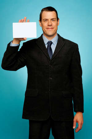 Isolated corporate man holding blank placard, showing it to cameraの写真素材