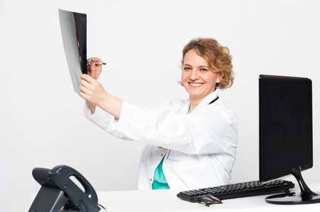 Surgeon pointing at diseased area with pen over x-ray report and looking at youの写真素材