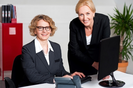 Woman working in office with colleague in front of computerの写真素材
