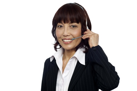 Cheerful asian customer support operator wearing headsets isolated over white backgroundの写真素材