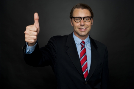 Businessman showing thumbs up sign to his team. Awesome performance by his teamの写真素材
