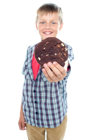 Sweet little boy offering you a chocolate cookie isolated over white backgroundの写真素材