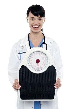 Enthusiastic medical officer displaying a weighing scale.の写真素材
