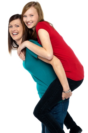 Happy mother giving piggy back ride to her daughter isolated on white background.の写真素材